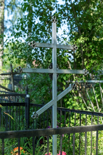 Cruz de hierro ortodoxa en una tumba en un cementerio cristiano en verano vegetación Memoria y tristeza Vertical