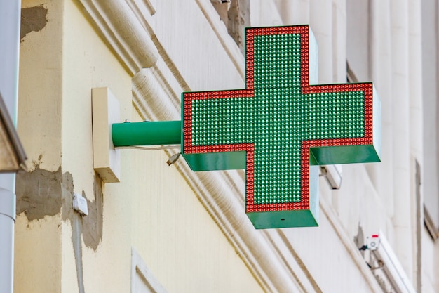 Cruz LED verde instalada en la pared sobre la entrada a la farmacia