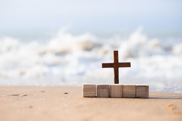 Una cruz de madera en la arena de la playa.