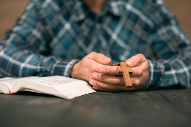 Cruz de madera de mano de hombre con Biblia