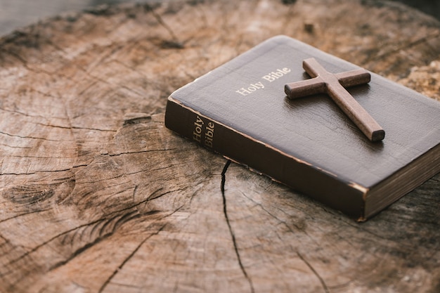 Foto una cruz de madera sobre la santa biblia sobre la mesa de madera lecturas dominicales educación bíblica