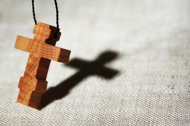 Foto cruz de madera con sombra profunda sobre fondo de madera