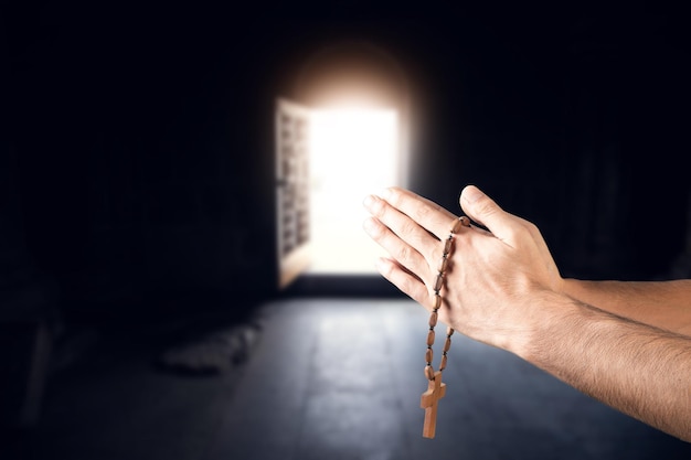 Cruz de la mano del hombre de oración en el fondo de la iglesia