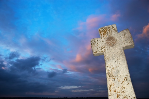 Cruz de piedra sobre fondo de cielo oscuro