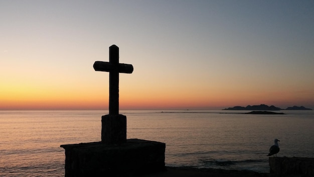Cruz en la playa contra el cielo durante la puesta de sol