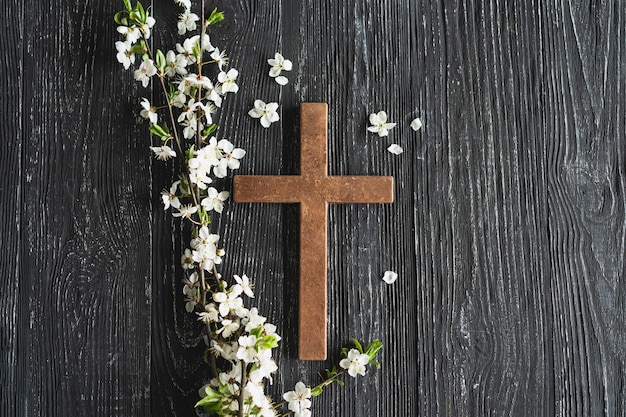 Foto cruz que simboliza la muerte y resurrección de jesucristo flores de primavera sobre un fondo de madera