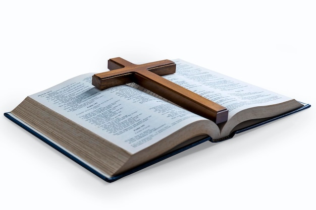 Cruz religiosa de madeira e livro azul aberto da Bíblia Santa isolado sobre fundo branco Feriado cristão religioso Símbolo de fé em Deus Festa cristã