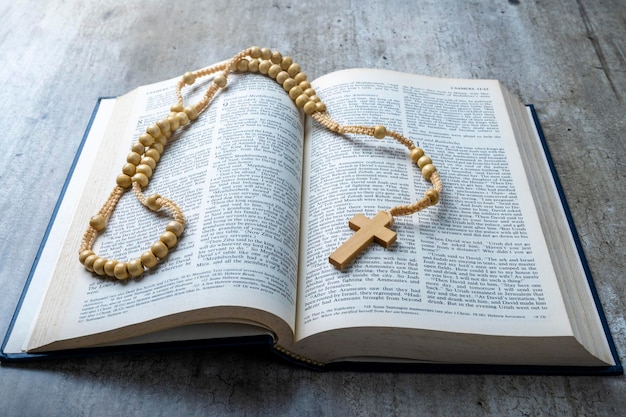 Cruz religiosa de madeira em contas de rosário e livro azul aberto da Bíblia Santa Está deitado em uma mesa de madeira Festa cristã religiosa Símbolo de fé em Deus Festa do cristianismo