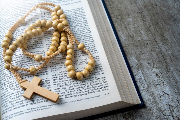 Cruz religiosa de madeira em contas de rosário e livro azul aberto da Bíblia Santa Está deitado em uma mesa de madeira Festa cristã religiosa Símbolo de fé em Deus Festa do cristianismo