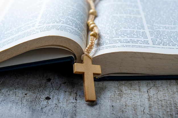 Cruz religiosa de madeira em contas de rosário e livro azul aberto da Bíblia Santa Está deitado em uma mesa de madeira Festa cristã religiosa Símbolo de fé em Deus Festa do cristianismo
