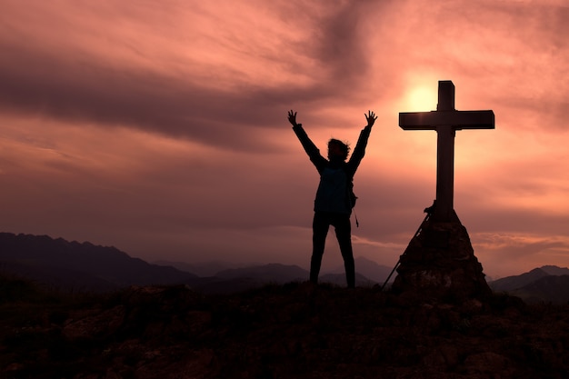 Cruza en la cima de la montaña con un alpinista que levanta las manos