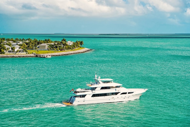 Cruzeiro turístico de barco ou iate flutuando perto da ilha com casas e árvores verdes em águas turquesa e céu azul nublado, iatismo e esporte, viagens e férias, Key West Florida, EUA