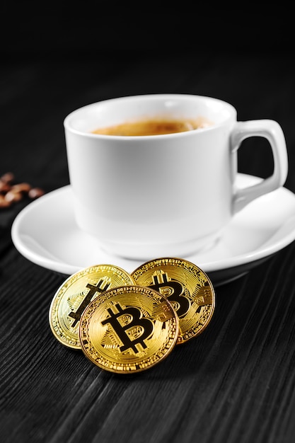 Cryptocurrency golden bitcoin que se coloca en la taza de café aislada