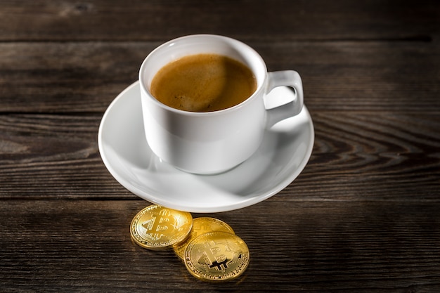 Cryptocurrency golden bitcoin que se coloca en la taza de café aislada