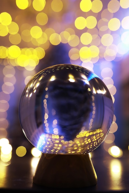 Foto crystal ball no chão com bokeh, luzes atrás. bola de vidro com luz colorida bokeh, conceito de celebração de ano novo.