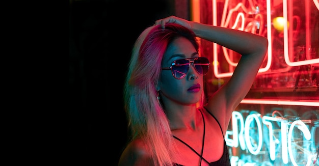 CU Retrato noturno de asiáticos em pé nas ruas cheias de luzes de neon. fundo neon