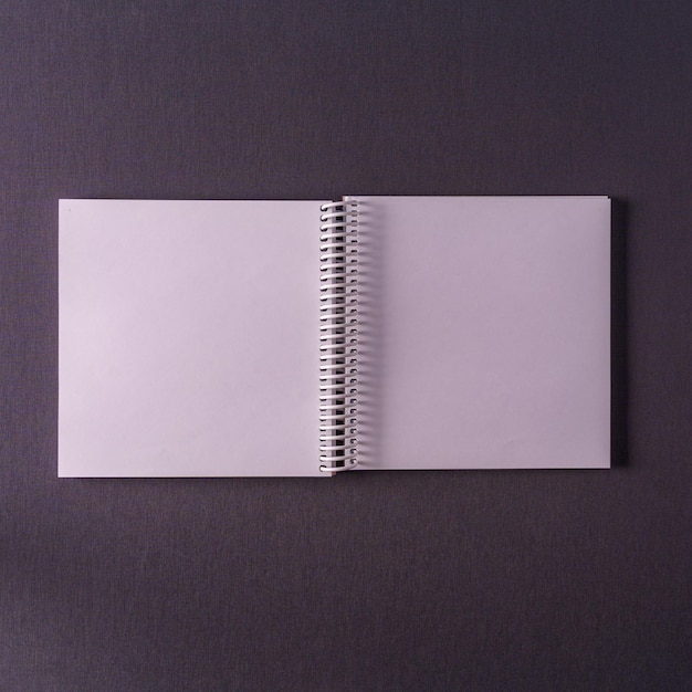 Un cuaderno A4 vacío en forma expandida en una maqueta de vista superior de fondo con textura gris