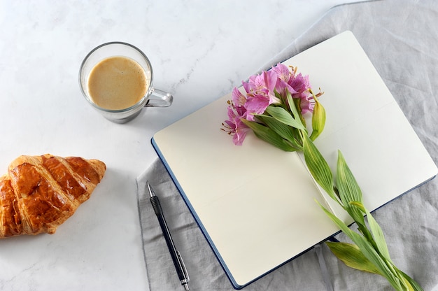 Cuaderno abierto con flores de lirio y café negro