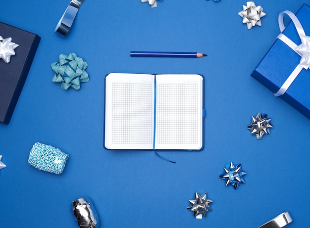 Cuaderno abierto con hojas blancas vacías, fondo azul con caja