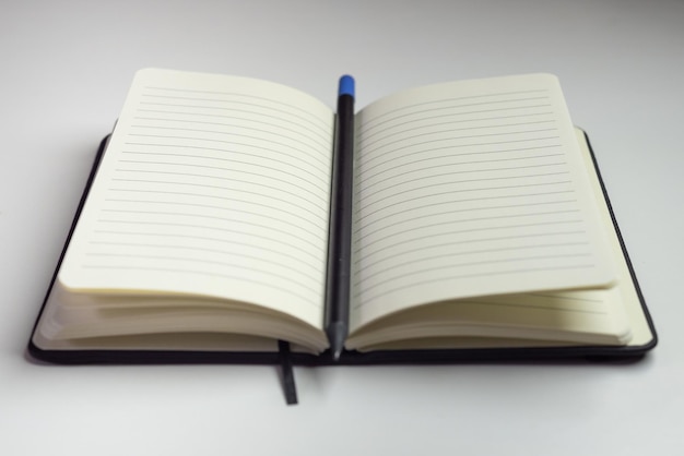 Cuaderno abierto con hojas blancas vacías con líneas horizontales y un lápiz con fondo blanco
