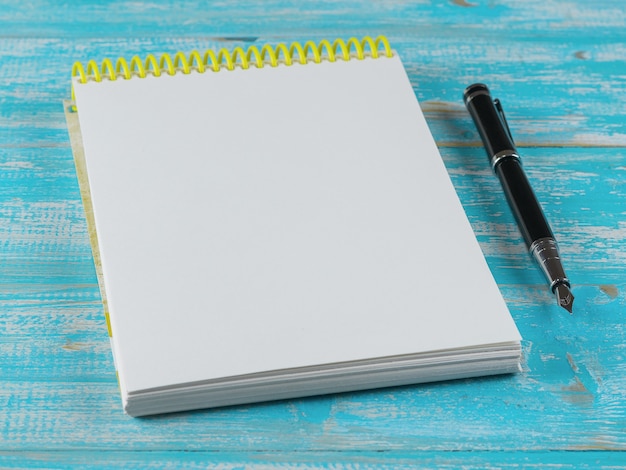 Cuaderno abierto con una pluma estilográfica sobre una mesa de madera azul