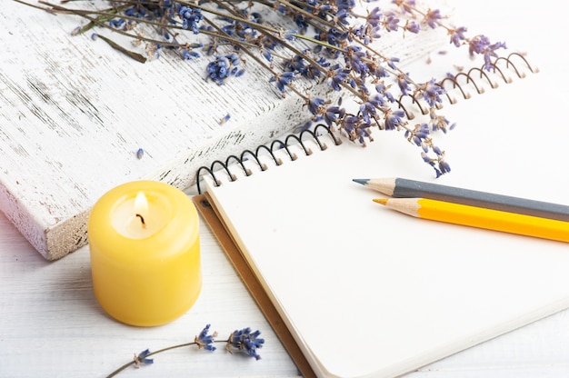 Cuaderno abierto vacío con flores de lavanda secas. Arreglo de aromaterapia, bodegón zen con velas encendidas