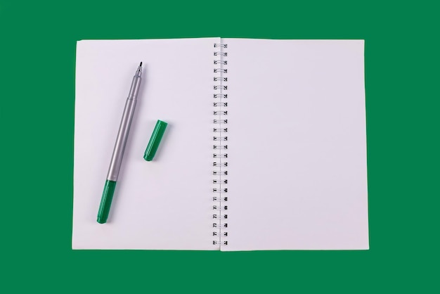 Cuaderno abierto de vista superior en color verde con marcador en el espacio de copia de fondo verde