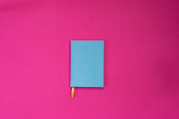 Cuaderno azul en blanco para su inscripción en un fondo de verano rosa