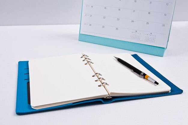 Foto un cuaderno azul con un bolígrafo se encuentra en un escritorio junto a un calendario que dice 