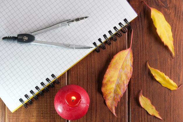 Cuaderno en blanco abierto con hojas a cuadros con brújulas sobre fondo de madera marrón