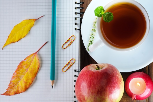 Cuaderno en blanco abierto con hojas a cuadros con un lápiz junto a una taza de té caliente