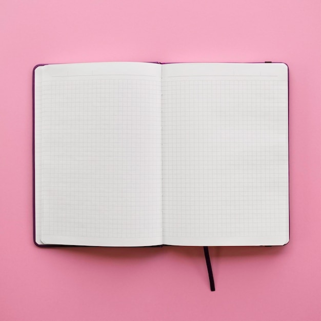 Cuaderno en blanco abierto sobre fondo rosa