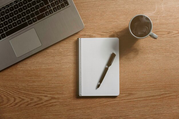 Cuaderno en blanco con un bolígrafo, un calendario, un cuaderno y un concepto de café caliente, metas y plan de acción para el año nuevo