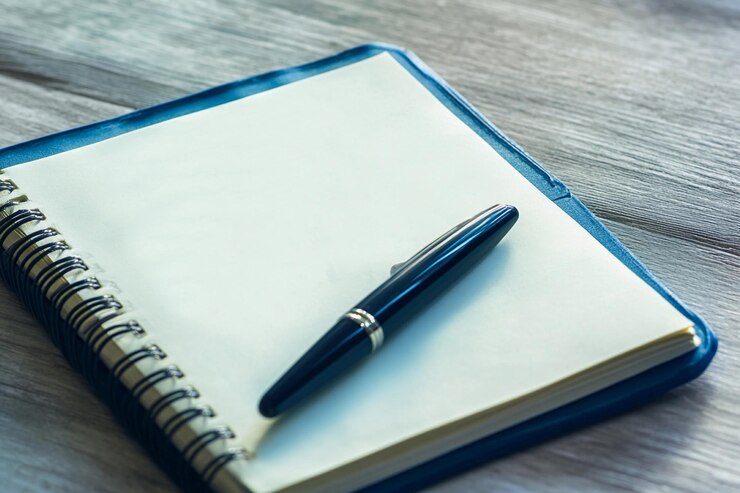 Cuaderno en blanco y bolígrafo en una mesa de madera listos para escribir ideas IA generativa