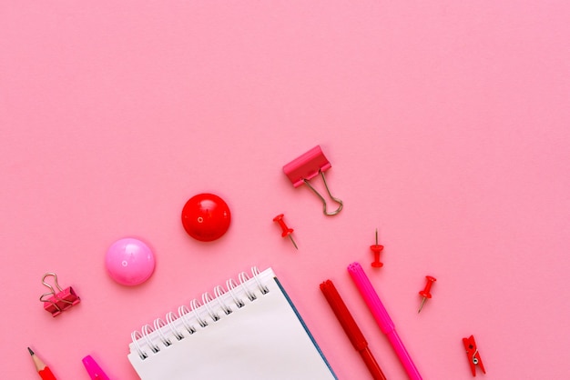 Cuaderno blanco se encuentra en forma de espacio en blanco sobre fondo rosa con bolígrafo rojo con marcadores útiles escolares ...