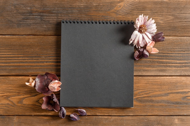 Cuaderno en blanco con flor en mesa de madera vintage