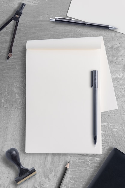 Cuaderno en blanco y herramienta de la oficina de la pluma en el fondo de la mesa de hormigón