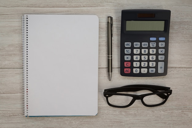 Un cuaderno en blanco con un lápiz y una calculadora.