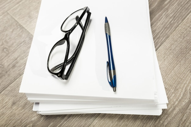 Cuaderno en blanco y lápiz con gafas en la mesa de madera