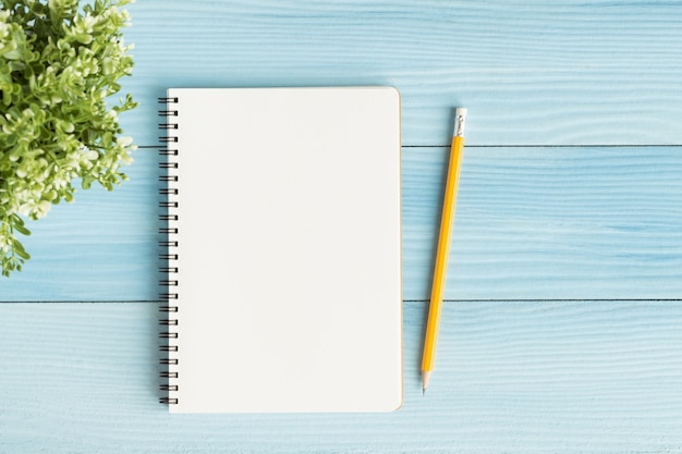 Cuaderno en blanco con y lápiz sobre fondo azul