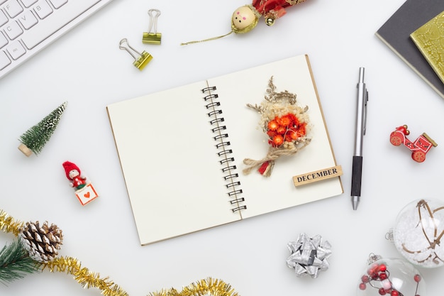 Cuaderno en blanco en la mesa de oficina blanca con adornos navideños