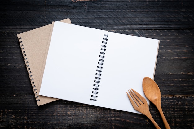 cuaderno en blanco para nota de texto sobre superficie de madera