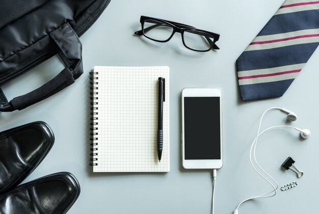 Cuaderno en blanco con la oficina de escritorio del teléfono móvil