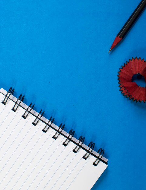 Cuaderno en blanco y papelería escolar sobre fondo azul oscuro