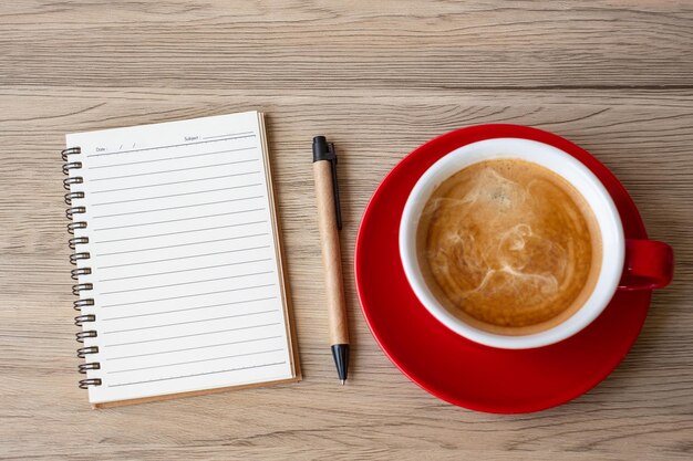 Cuaderno en blanco y taza de café en la mesa de madera. Motivación, resolución, lista de tareas pendientes, concepto de estrategia y plan