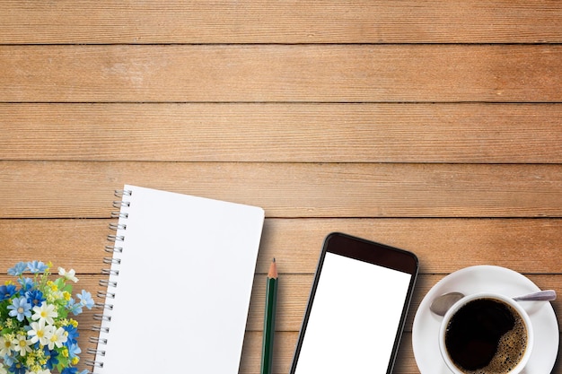 Cuaderno en blanco teléfono inteligente y taza de café en madera