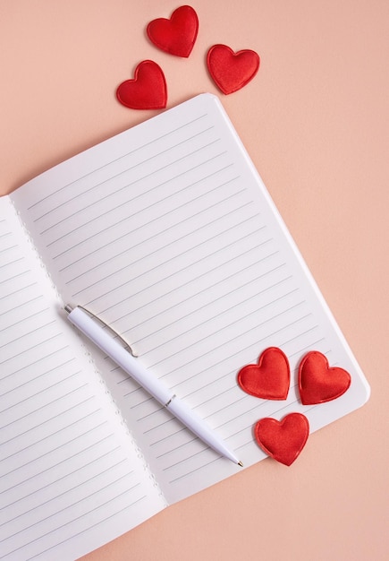 Un cuaderno con un bolígrafo y corazones en un fondo claro Valentín concepto día de las madres tarjeta de cumpleaños