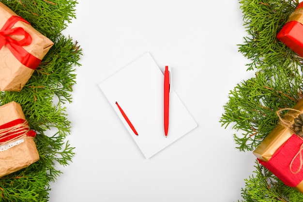 Cuaderno con bolígrafo junto a los regalos de Navidad