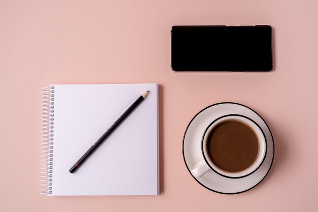 Cuaderno, bolígrafo, teléfono y una taza de café.