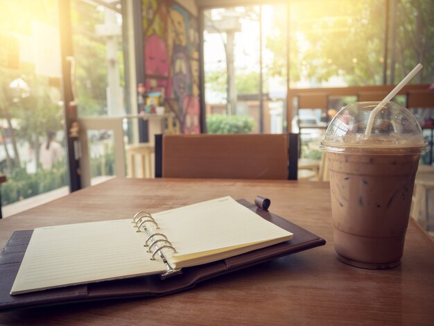 Cuaderno y café helado sobre fondo de madera